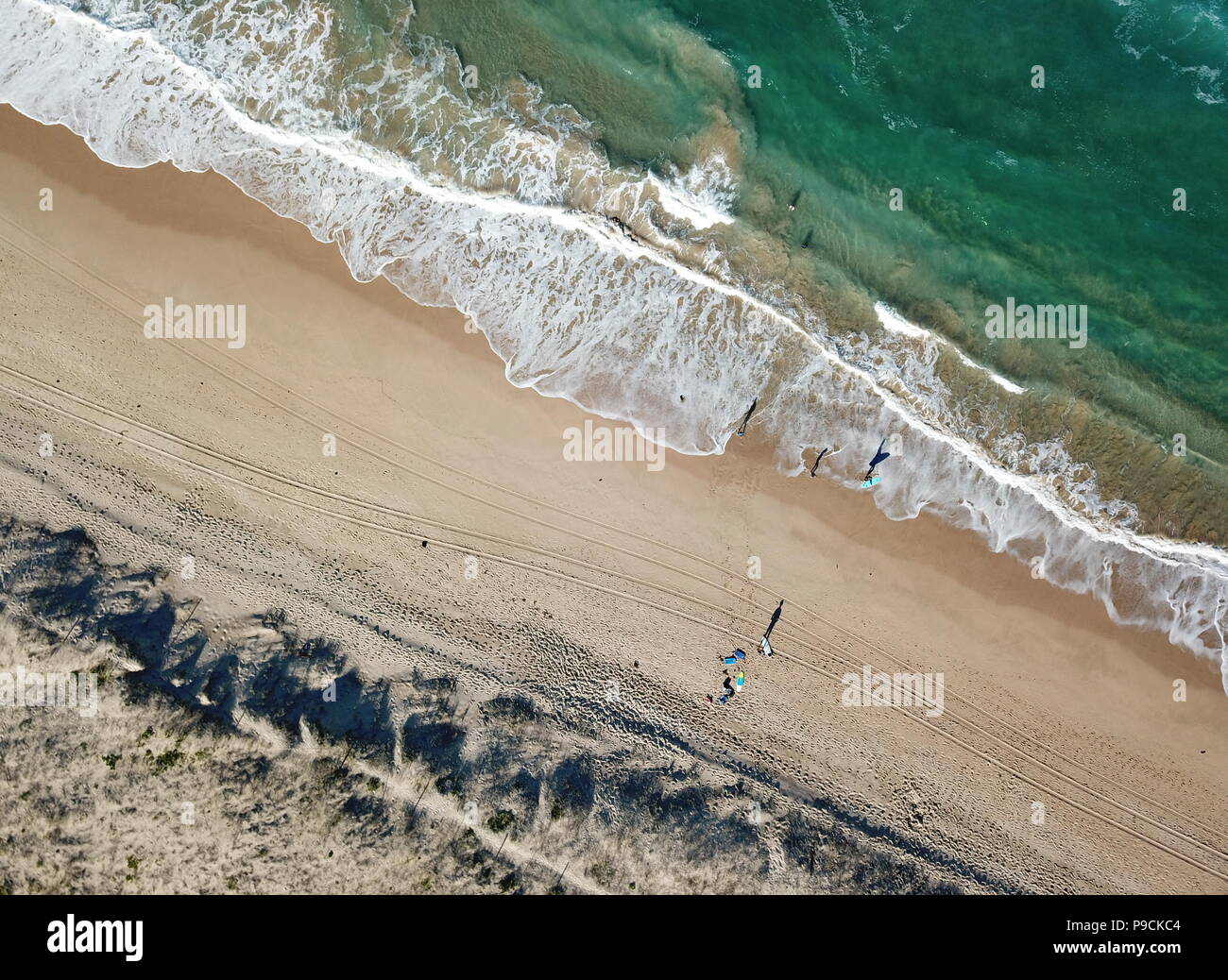 Marine mit Wellen und Schatten der gehenden Menschen. Ansicht von oben Luftbild aus fliegende Drohne von Natur Landschaft türkisfarbenes Wasser mit Wanda Strand in Win Stockfoto