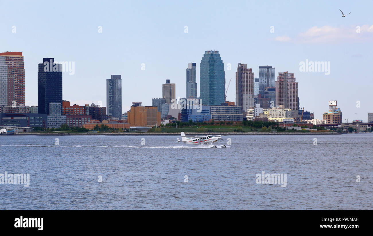 Ein Wasserflugzeug landet in New York City's East River mit Jägern zeigen, Queens im Hintergrund Stockfoto