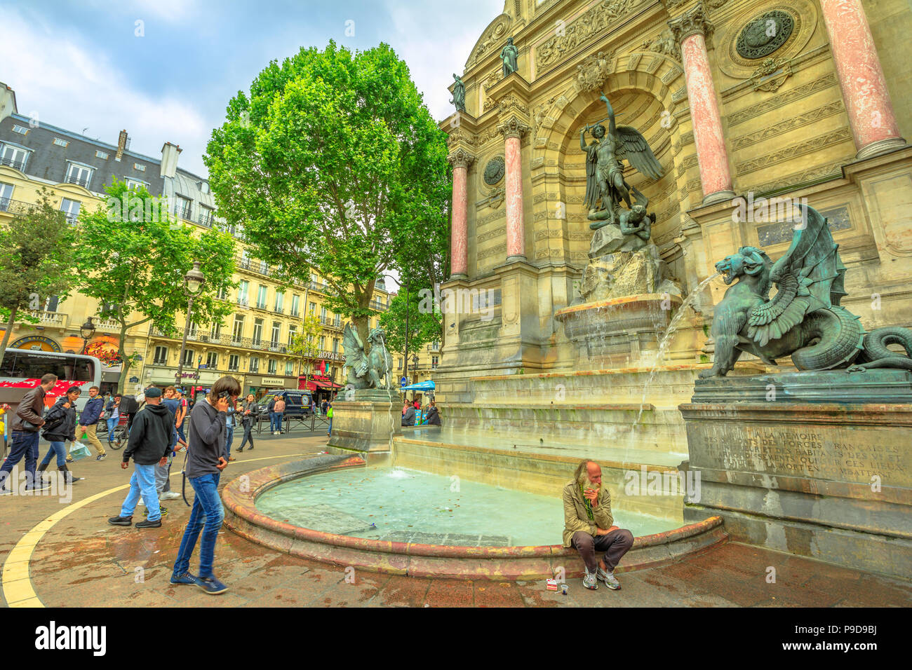 Paris, Frankreich, 1. Juli 2017: Clochard und Touristen in Place Saint-Michel und monumentale Fontaine Saint-Michel mit zwei wasserspeienden Drachen. Historischen städtischen Wahrzeichen in Paris. Stockfoto