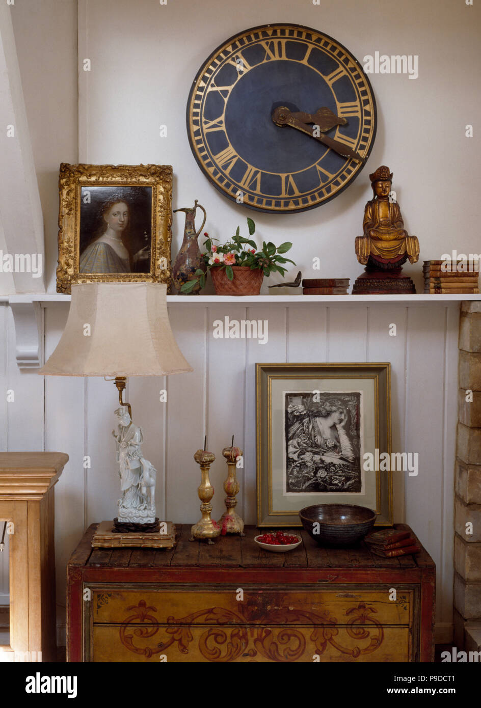 Runde Uhr auf Wand über Regal mit kleinen Buddha und goldgerahmten Bild  Stockfotografie - Alamy