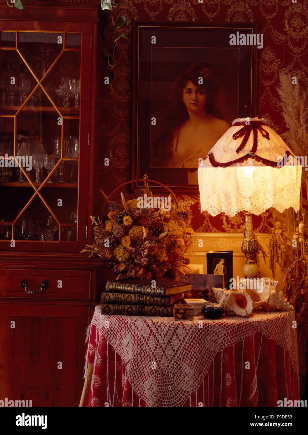 Getrocknete Blumen und Lampe mit spitzen Schatten auf Tabelle mit rosa Tuch in den 80er-Jahren rosa Esszimmer Stockfoto