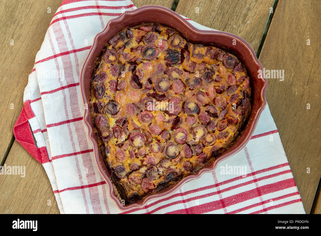 Ein clafouti mit Kirschen in Form von Herzen auf einen hölzernen Tisch Stockfoto