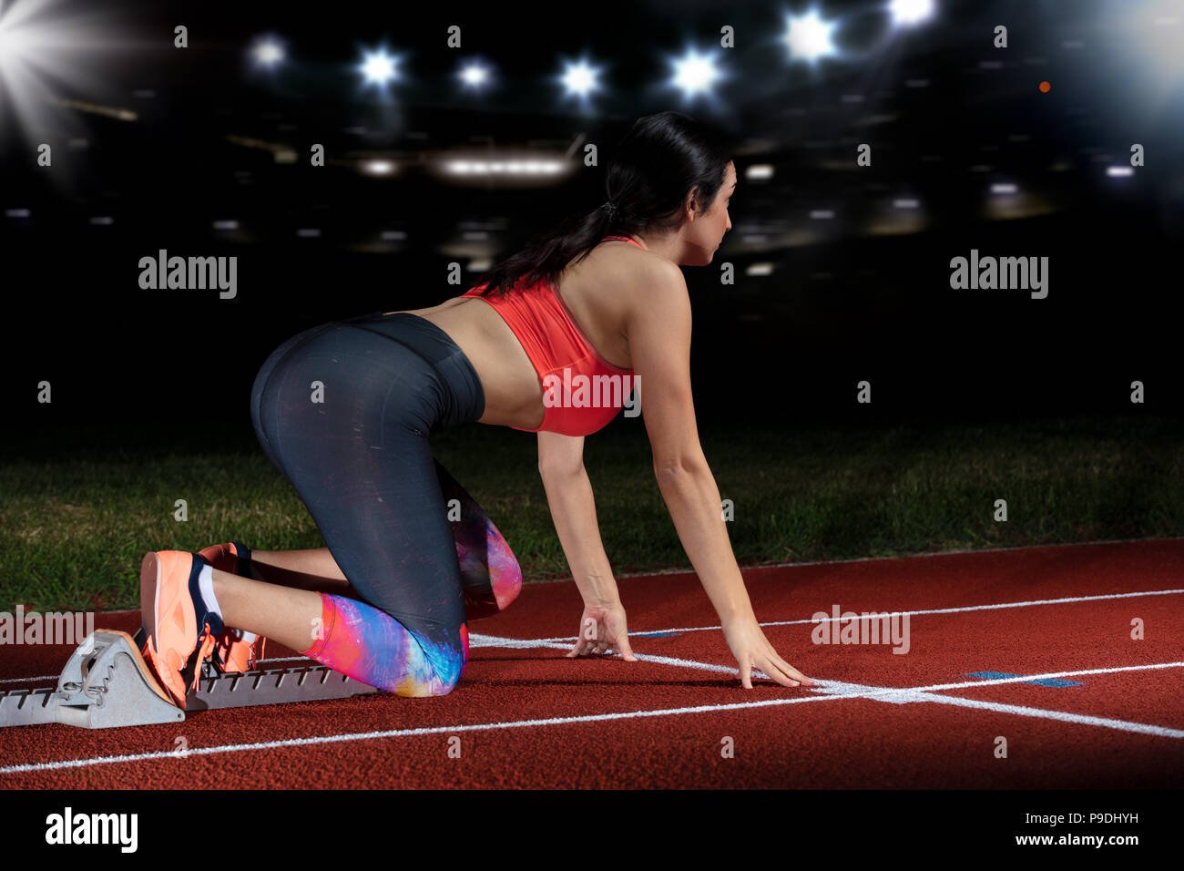 Frau Sprinter verlassen Start auf der Leichtathletikbahn. explodierende Start am Stadion mit Reflektoren Stockfoto