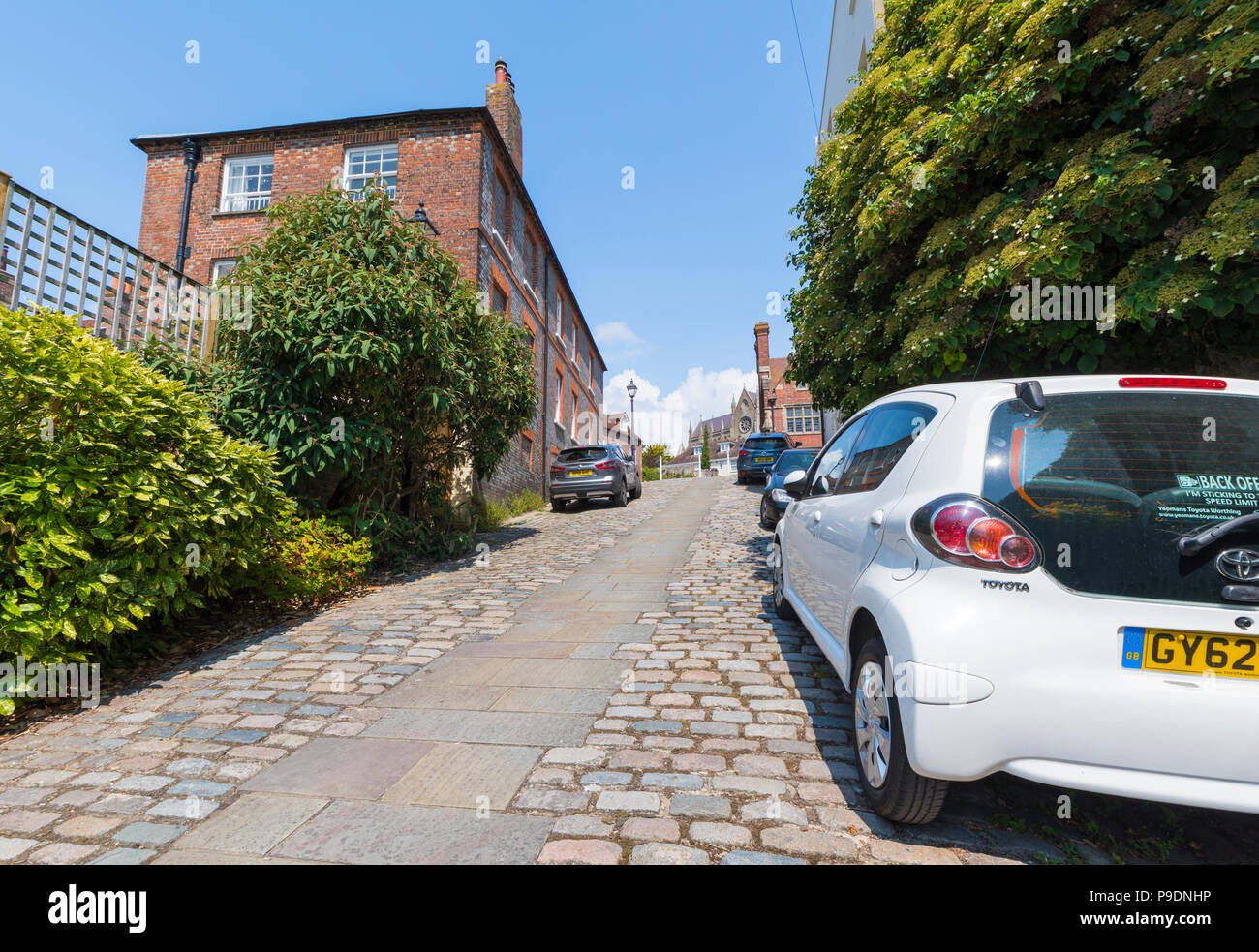 Autos auf Kings Arms Hill, einem historischen gepflasterten Straße auf einem steilen Hügel in der historischen Marktstadt in Arundel, West Sussex, England, UK geparkt. Stockfoto