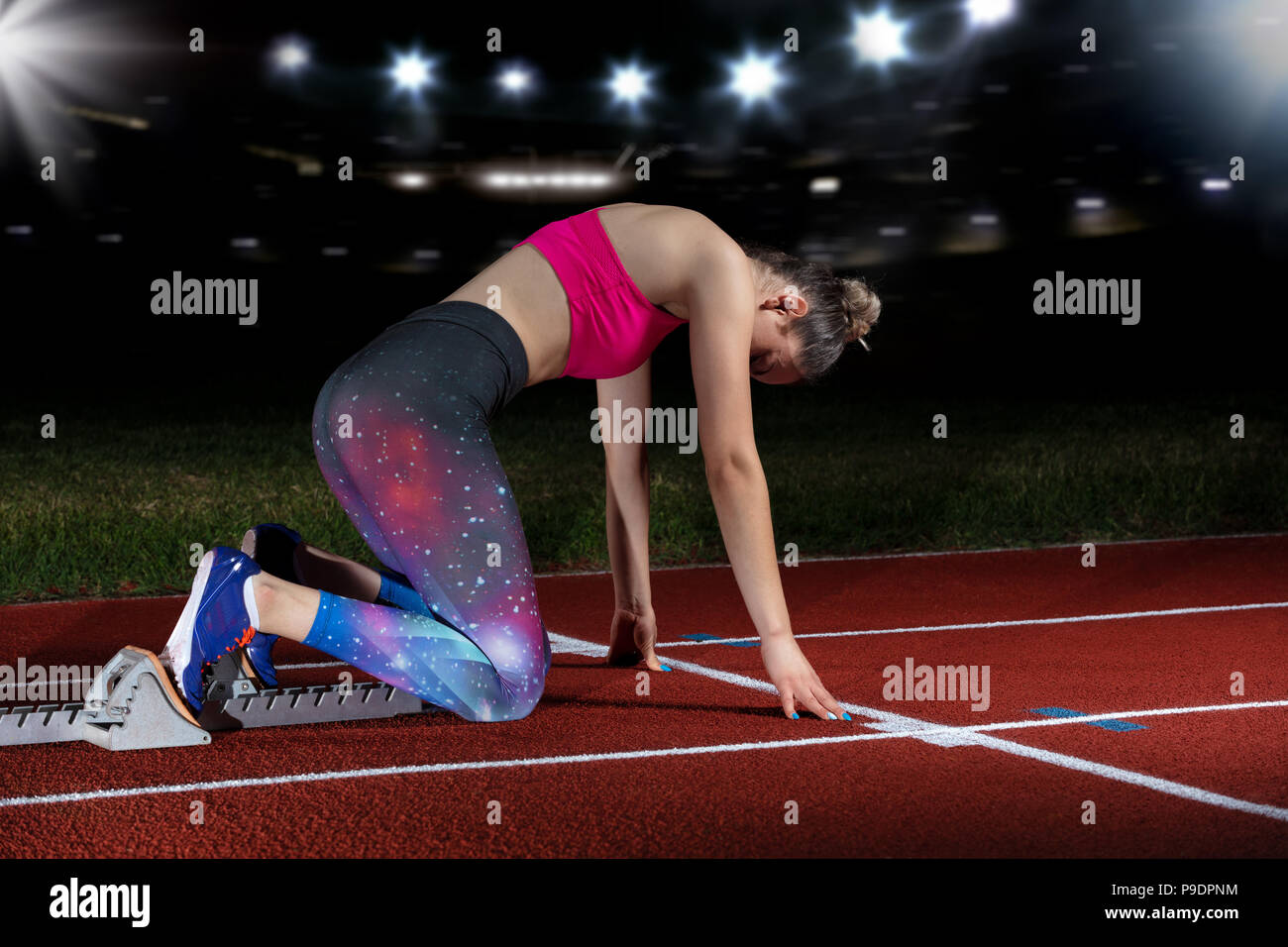 Frau Sprinter verlassen Start auf der Leichtathletikbahn. explodierende Start am Stadion mit Reflektoren Stockfoto