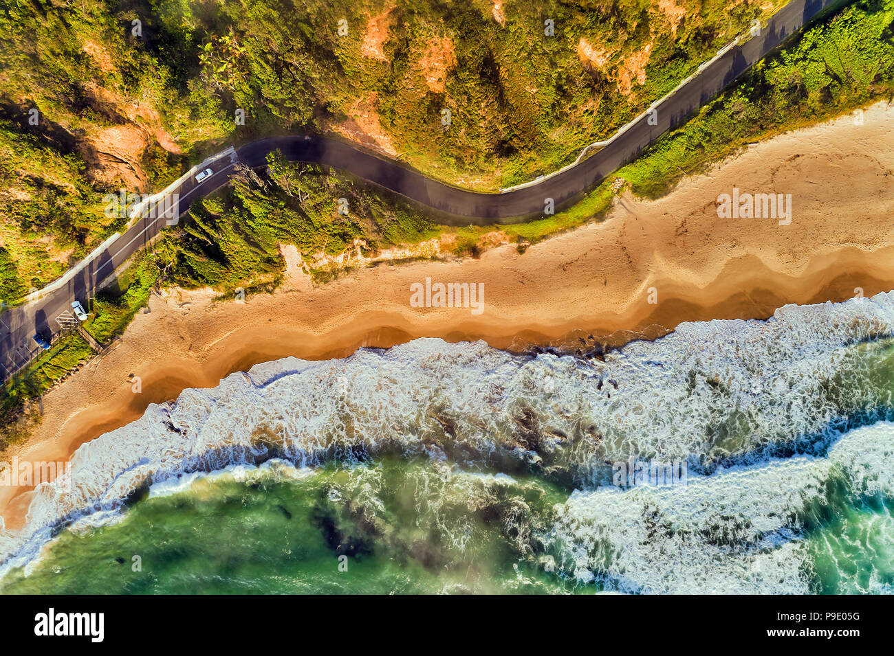 Breite Sandstrand unter Wellen des Pazifischen Ozeans mit lokalen Wohnstraße und Parkplatz entlang der Küste im Luftbild von Nambucca Heads lokalen Stockfoto