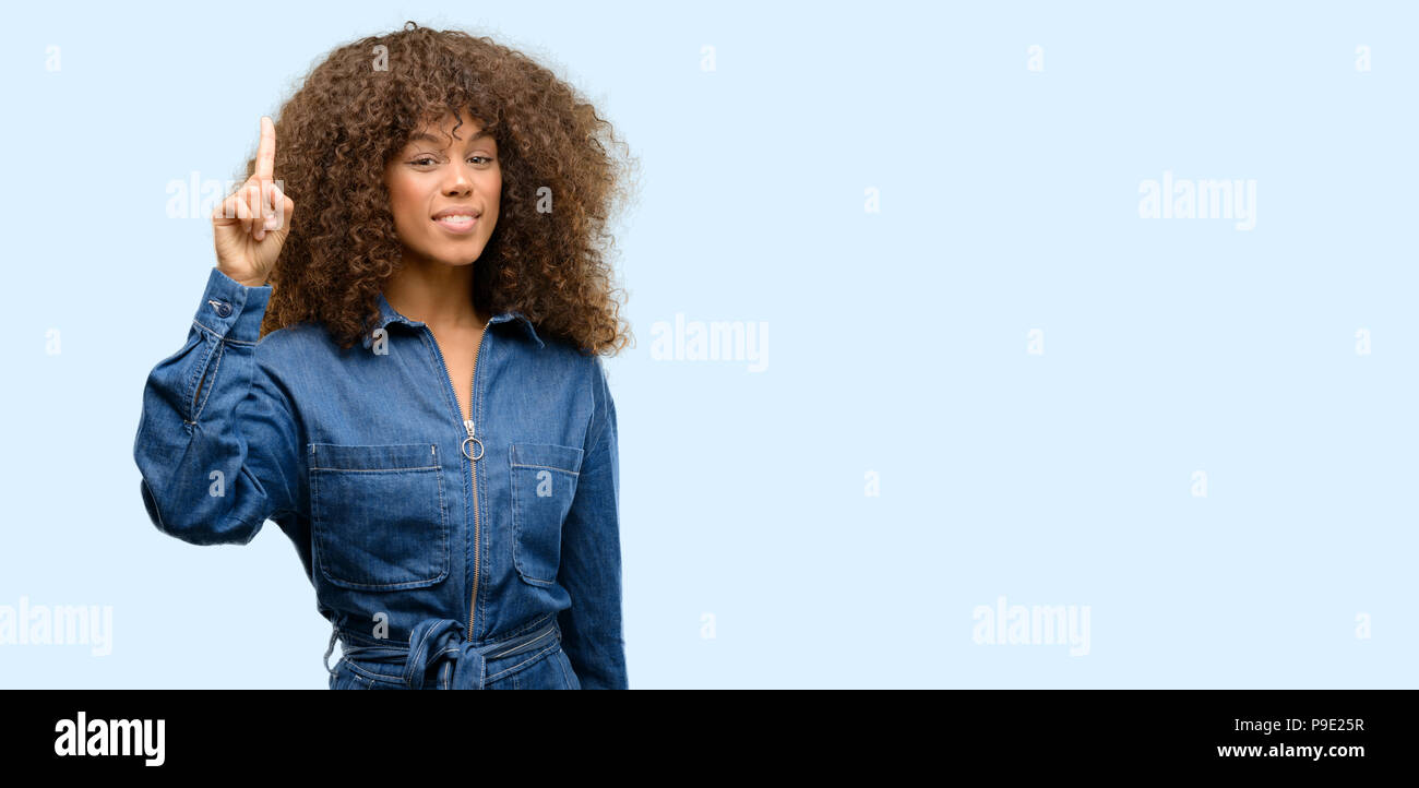 Afrikanische amerikanische Frau trägt blaue Jumpsuit, Finger, die Nummer eins Stockfoto