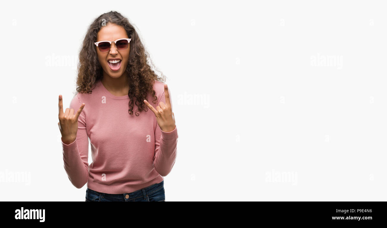 Schöne junge Hispanic Frau mit Sonnenbrille schreien mit verrückten Ausdruck tun Rock Symbol mit hands up. Musik Star. Schwere Konzept. Stockfoto