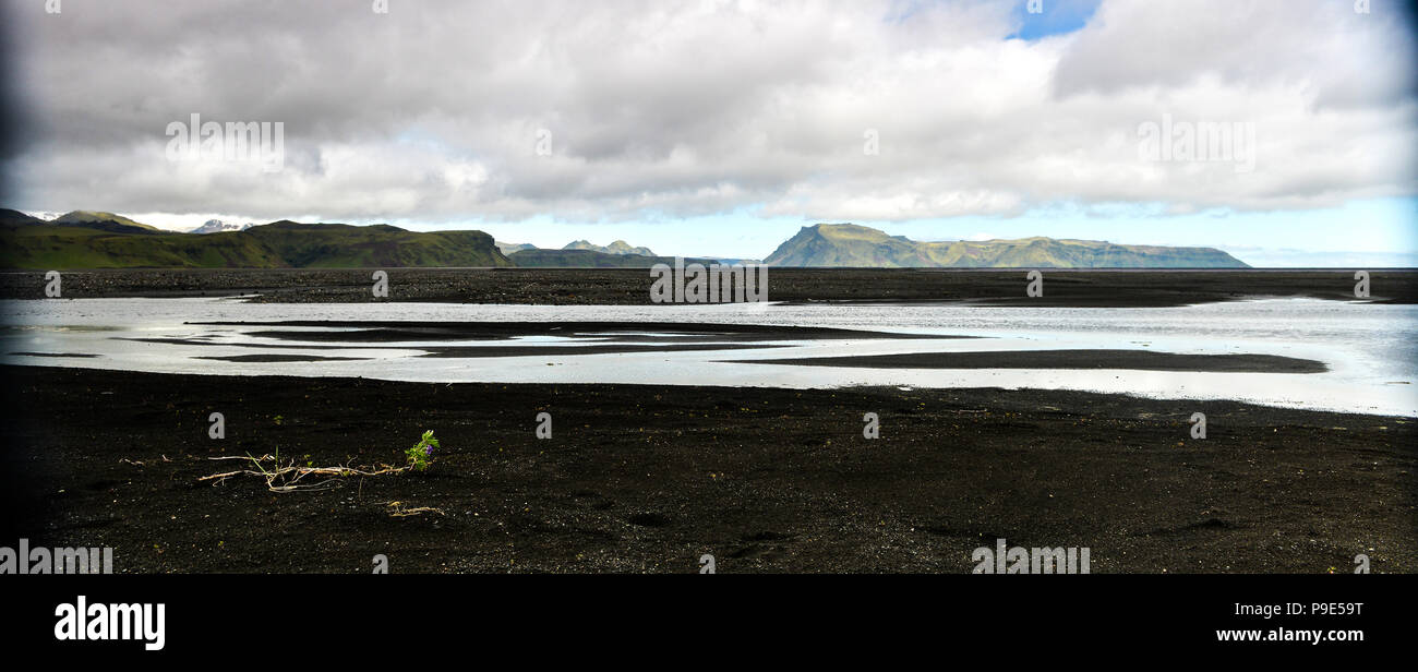 Eine isländische Landschaft mit schwarzem Sand und die Berge in der Ferne mit in den Vordergrund Boden ein Fluss Stockfoto