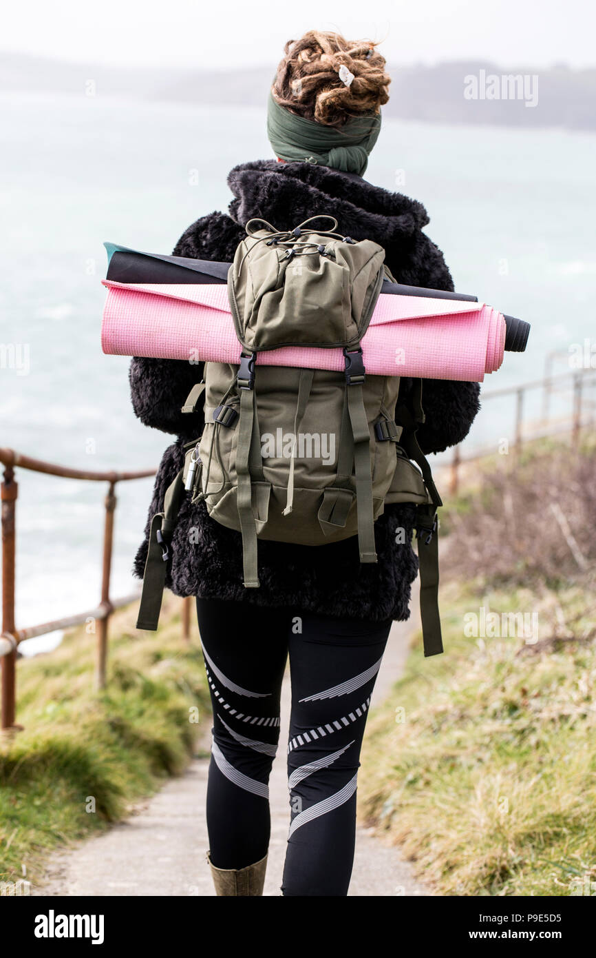 Ansicht der Rückseite des junge Frau mit braunen Haaren und Dreadlocks tragen Rucksack, entlang der Küsten Wanderweg. Stockfoto