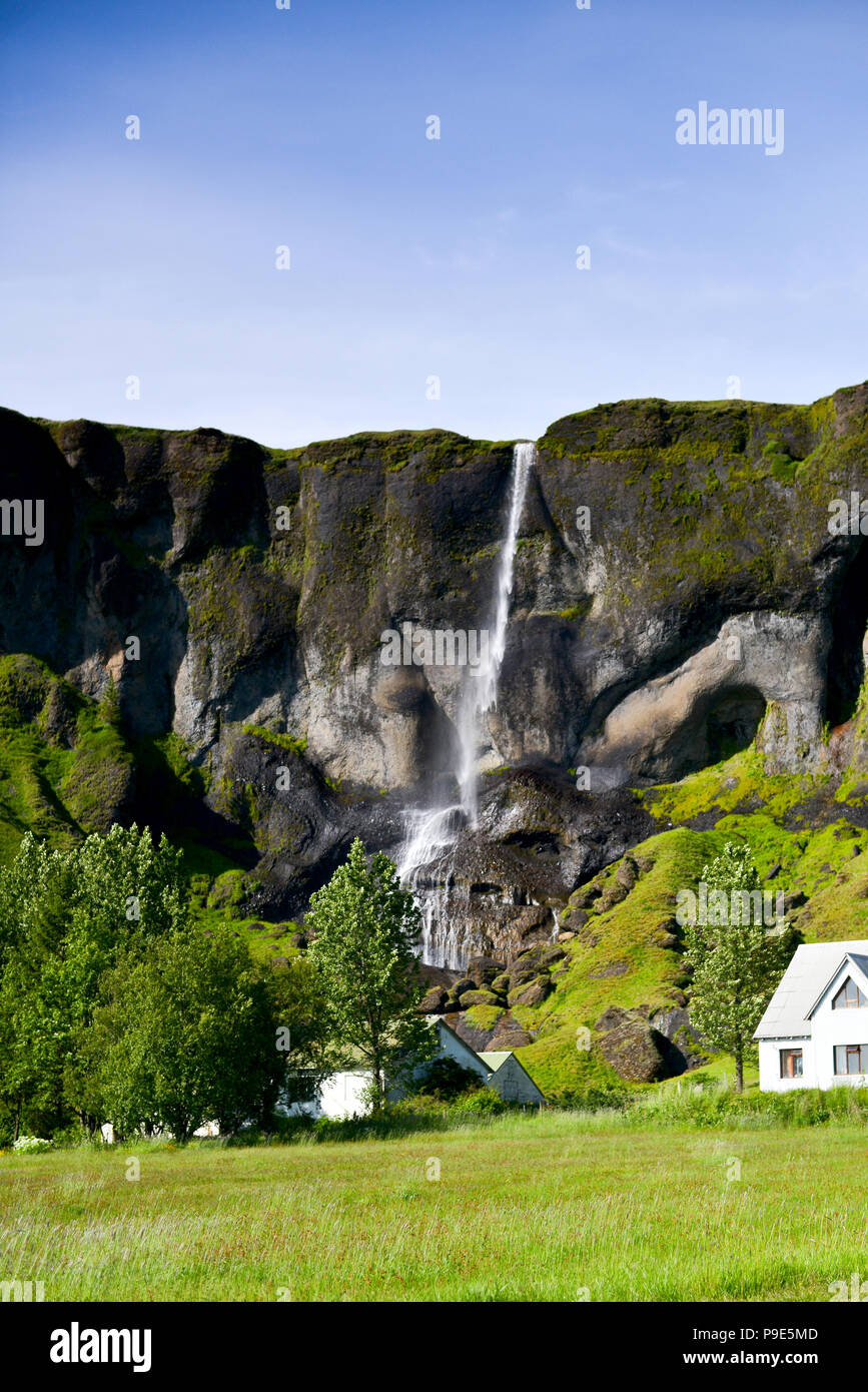 Eine isländische Wasserfall mit Haus darunter Stockfoto