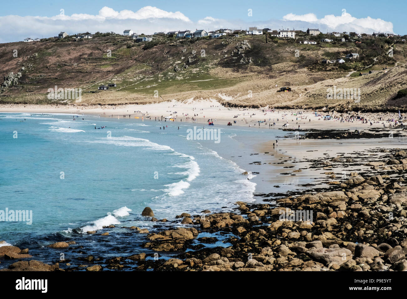 Blick entlang der Küste und Strand, Wellen brechen und die Menschen am Ufer, mit Häusern, auf dem mit Blick auf die Klippen. Stockfoto