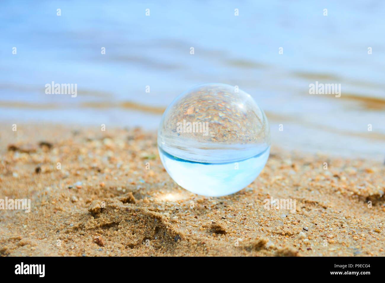 Glas Kugel am Sandstrand Stockfoto