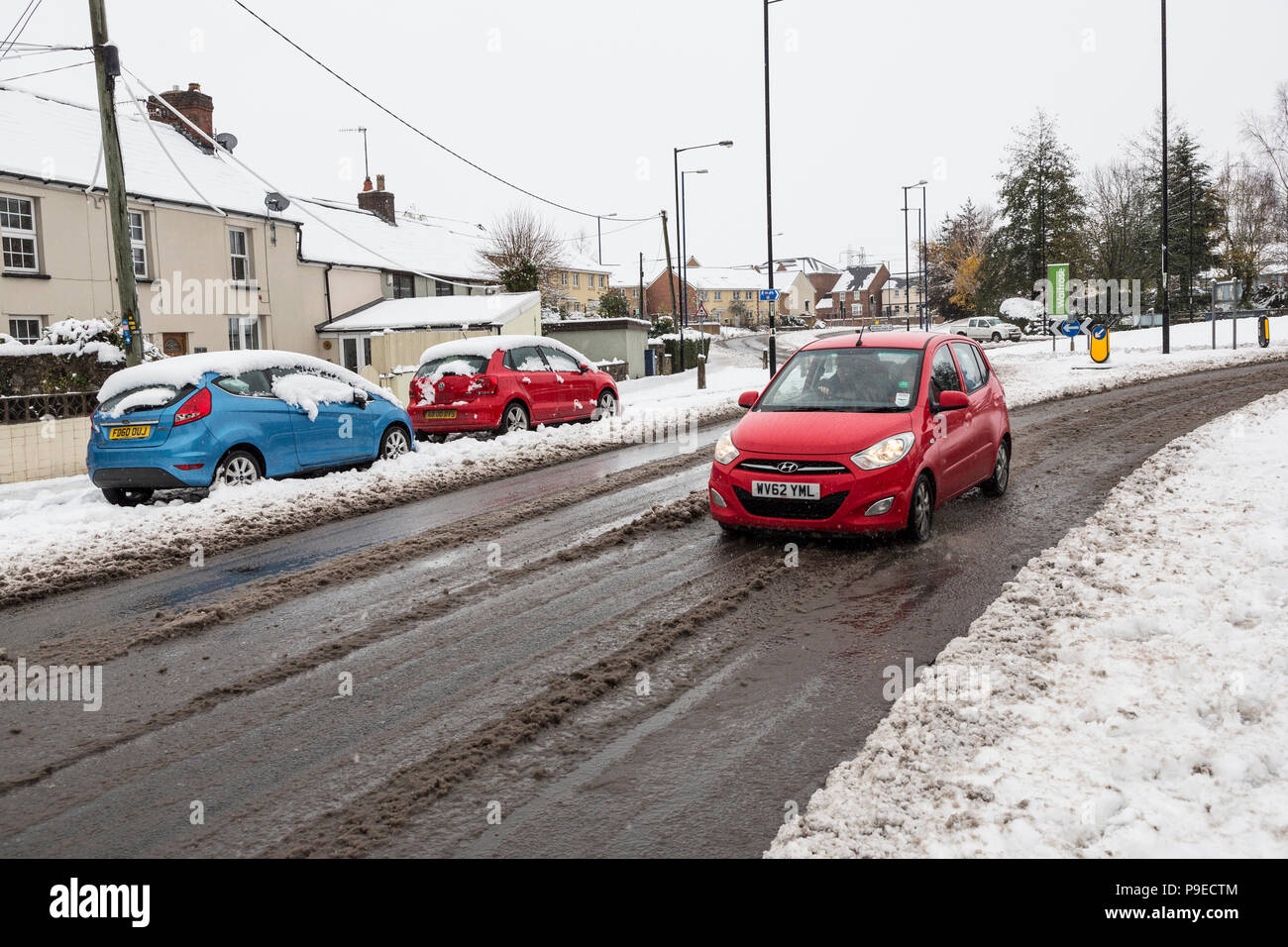 Autos fahren durch Schneematsch in Street, Abergavenny, Wales, Großbritannien Stockfoto