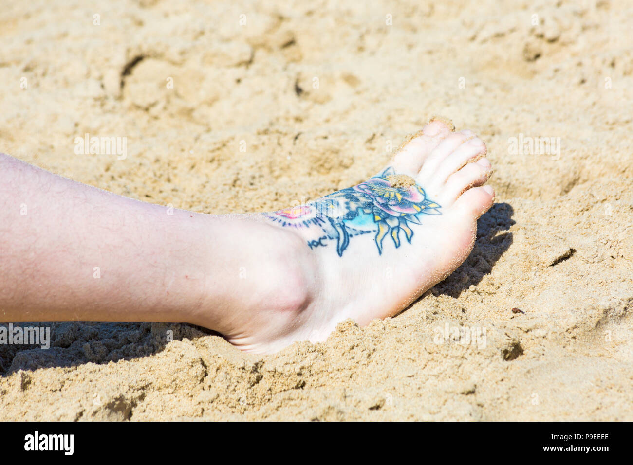Tattoo zu Fuß in den Sand der Mann am Strand in Branksome Dene, Poole, Dorset Großbritannien im Juli Stockfoto