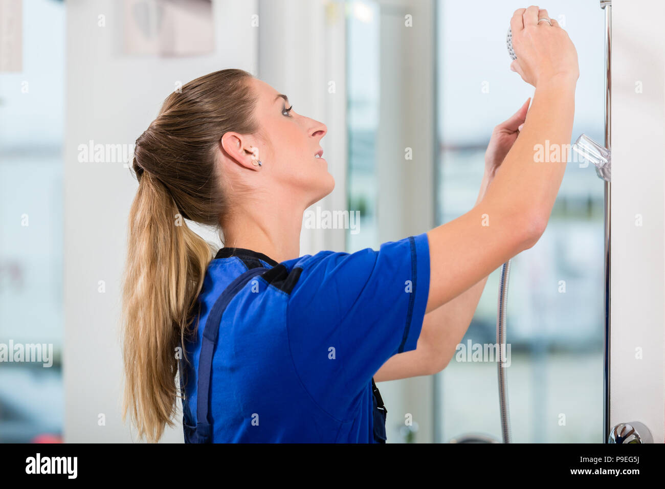 Qualifizierte Arbeitnehmerinnen Kontrolle einen Duschkopf in einem modernen Sanitär Shop Stockfoto