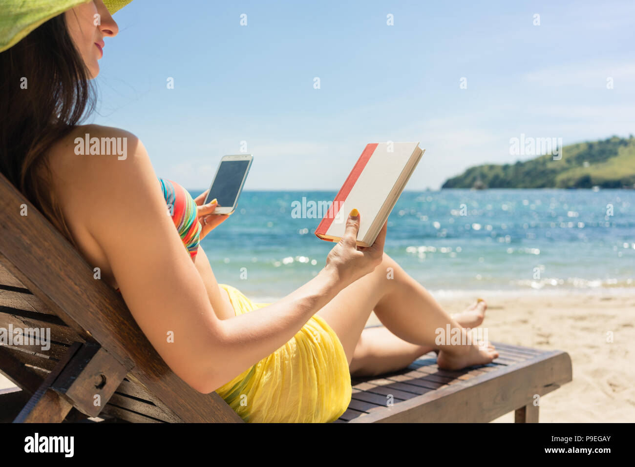 Junge Frau zwischen einem Buch und Zeit auf Internet unentschlossen Stockfoto