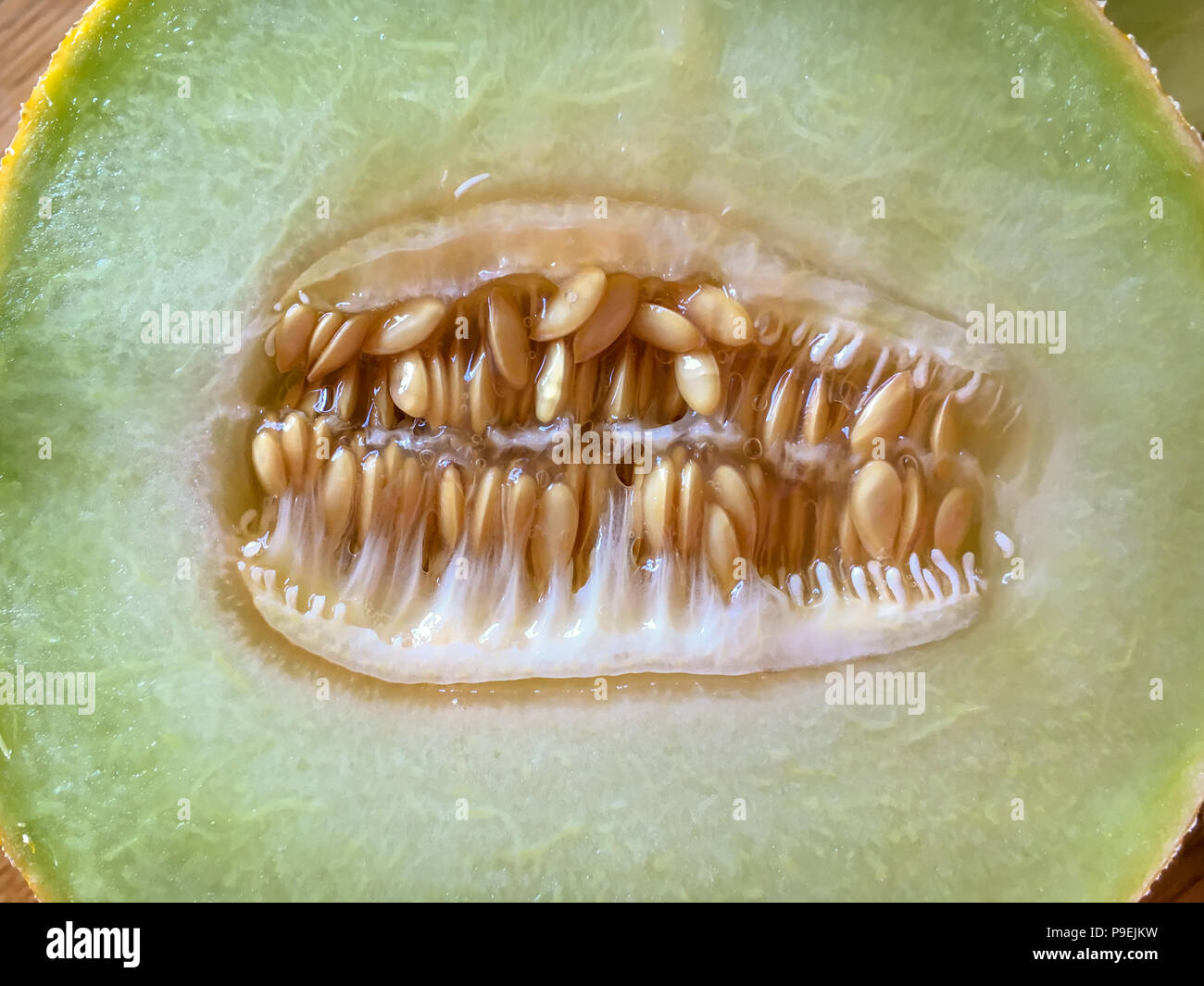 Die Hälfte der Zuckermelone auf dem hölzernen Hintergrund der Ansicht von oben Stockfoto