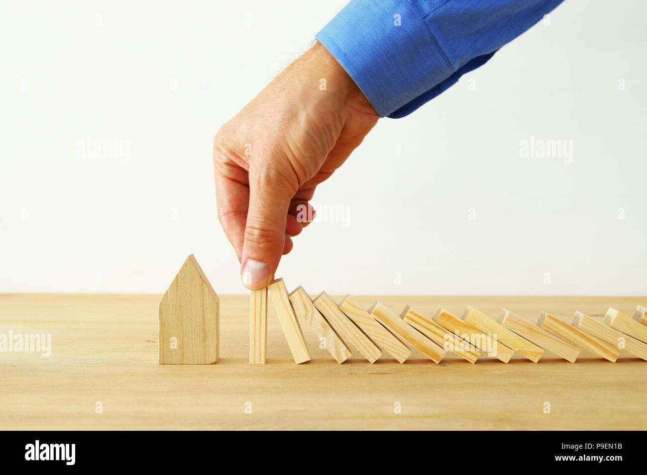 Konzept Bild von Immobilien Versicherungen und Schutz. Mann die Hände die Blockierung der Domino Effekt zu speichern, ein kleines Haus Stockfoto
