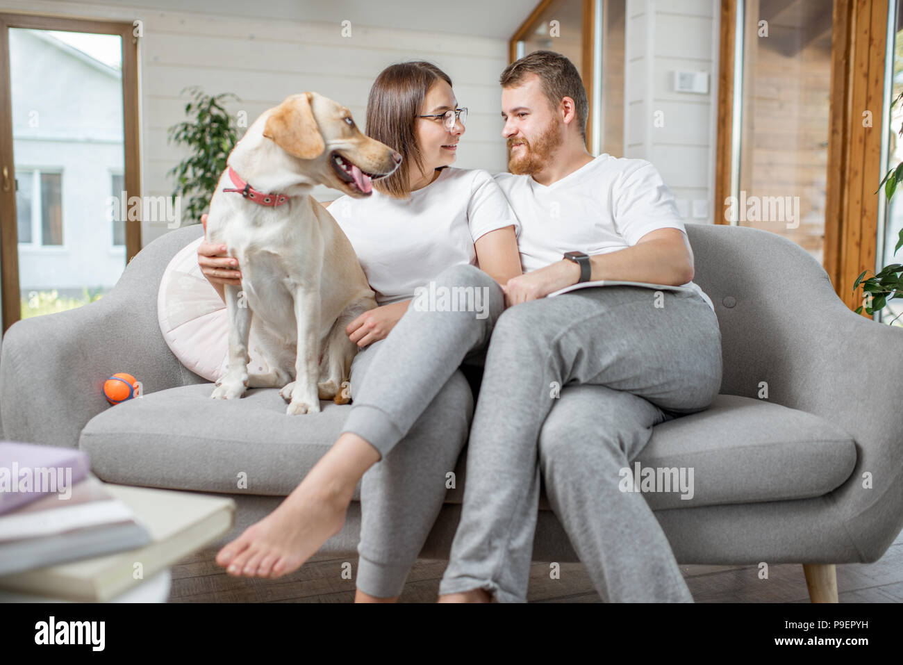 Paar mit Hund auf der Couch zu Hause Stockfoto