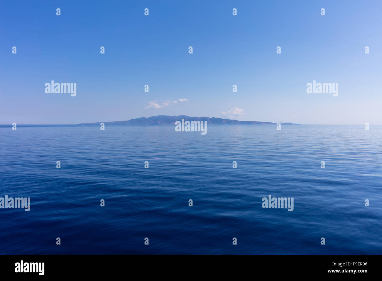 Griechenland. Ägäis, Kykladen. Kleine Insel der Kykladen auf blauen Himmel und ruhige See Wasser Hintergrund Stockfoto