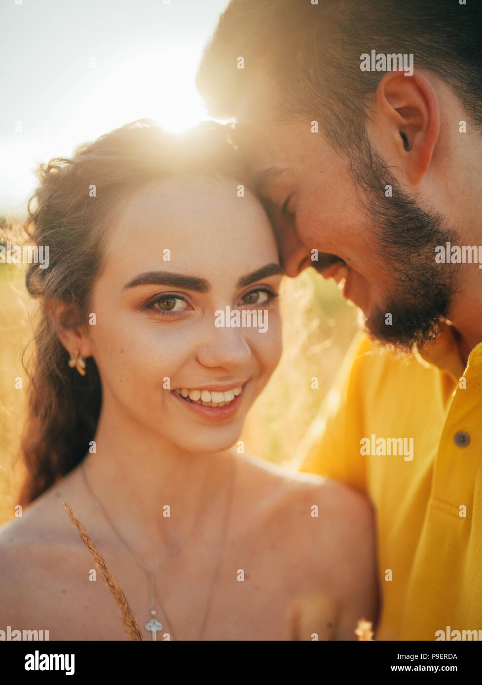 Portrait von lächelnden verliebte Paare an der Wiese. Mit Hintergrundbeleuchtung. Stockfoto