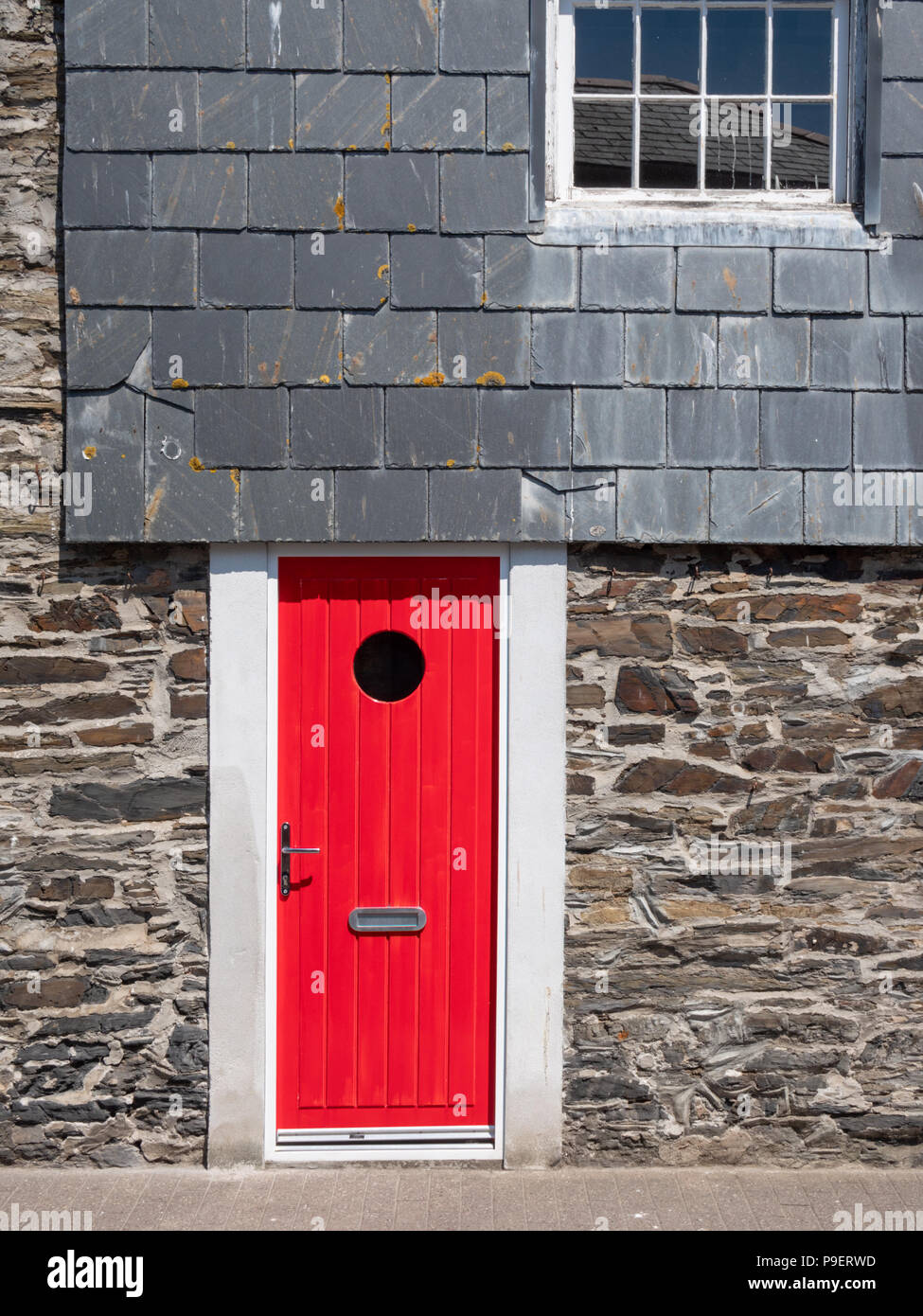 Eine helle rote Tür auf einem Granit und Schiefer Haus in Padstow Cornwall GROSSBRITANNIEN Stockfoto