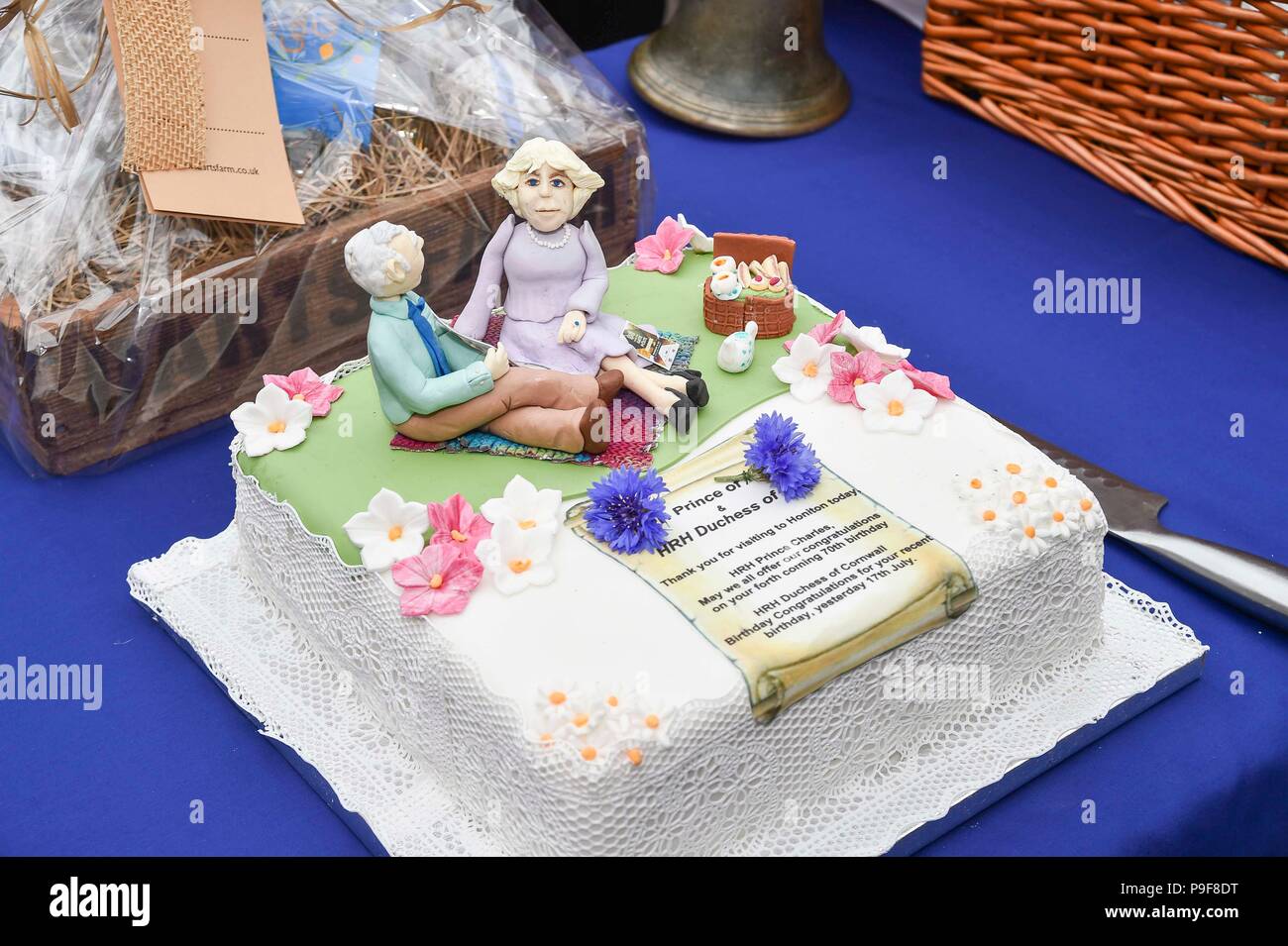 Honiton, Devon, Großbritannien. Juli 2018 18. Der Herzog und die Herzogin von Cornwall besuchen Sie das Gate Lebensmittelmarkt in Honiton, Devon an der Platte. Ein commemorative Kuchen mit Miniatur Figuren des Herzogs und der Duckess von Cornwall. Foto: Graham Jagd-/Alamy leben Nachrichten Stockfoto