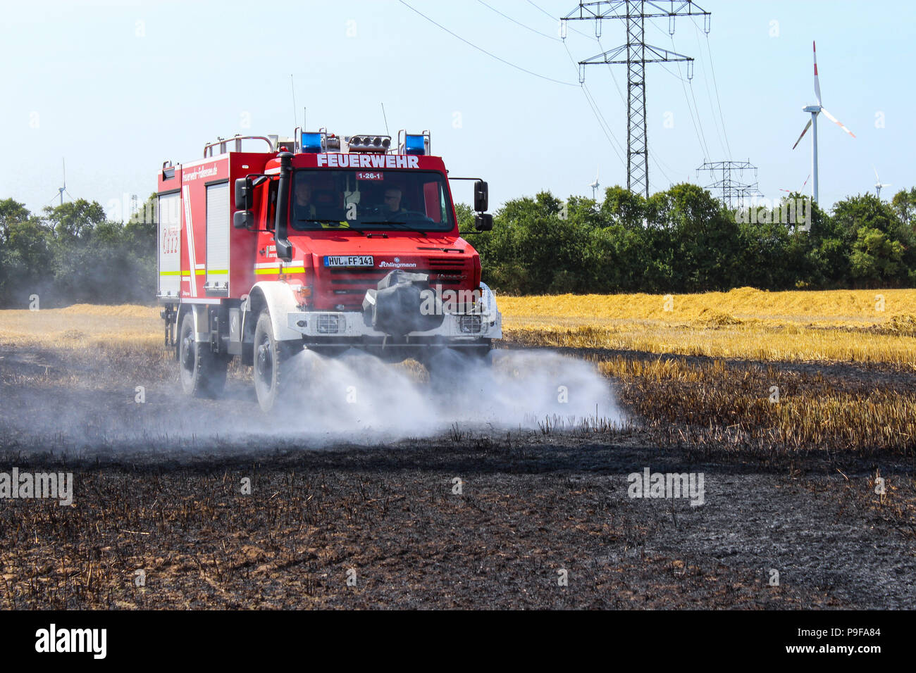 Brieselang, Deutschland. 18 Juli, 2018. Ein feuerwehrauto Löschen eines Brandes auf ein Maisfeld. Das Feld in Brand während des Mähens funktioniert. Die anhaltende Hitze stört die Landwirte. Credit: Julian 1603/DPA/Alamy leben Nachrichten Stockfoto