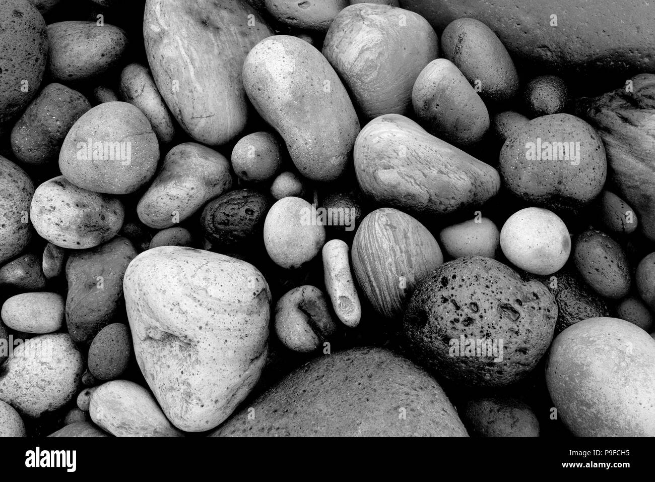 Runde Kieselsteine/Steine/Felsen am Strand auf den Azoren in Schwarz und Weiß Stockfoto