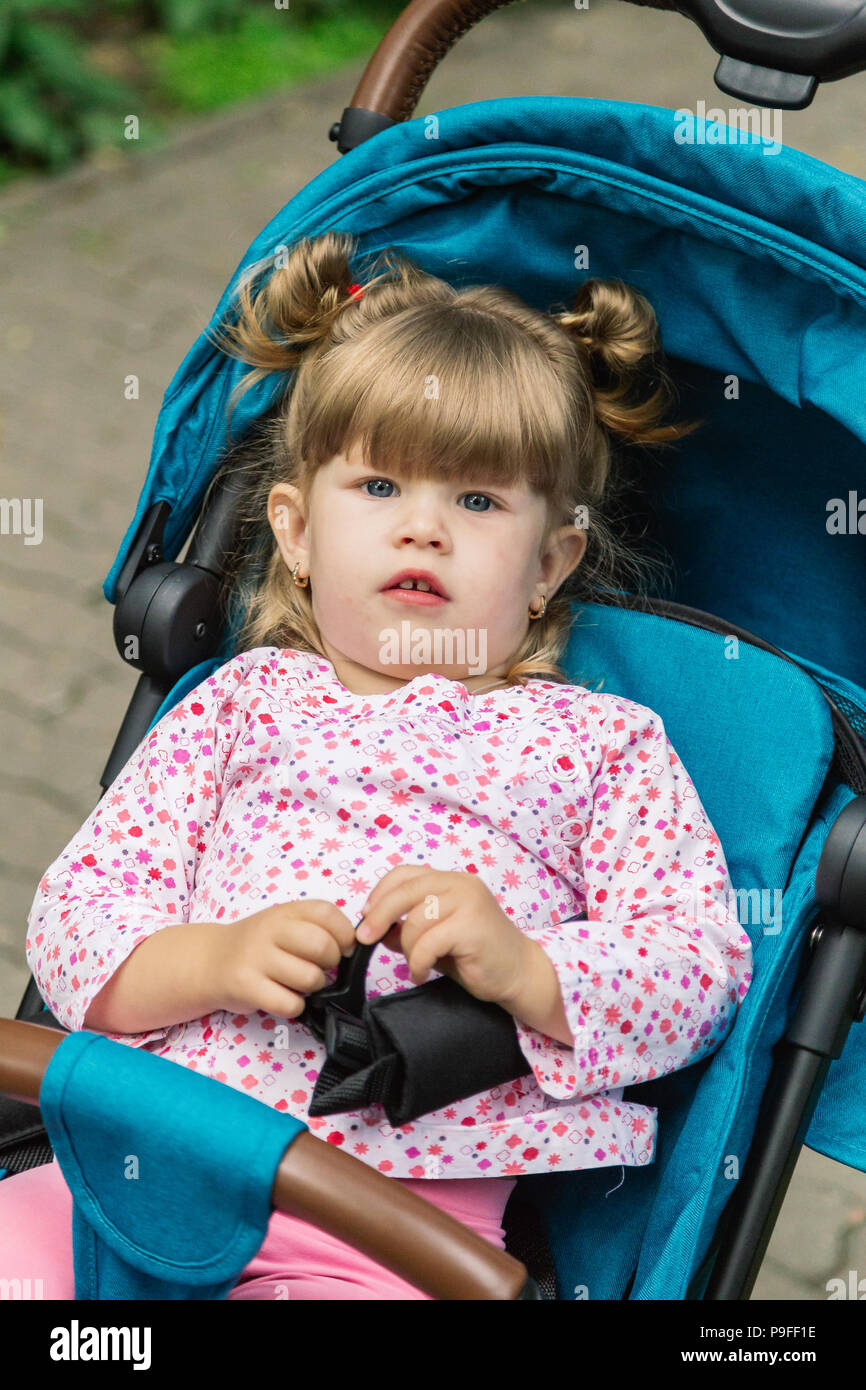 Kleines Mädchen sitzt in einem Kinderwagen in einem schönen Park  Stockfotografie - Alamy