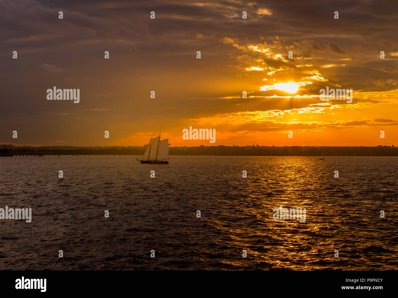Spektakuläre Sonnenuntergang Blick auf den Hafen von New York mit Segelboot vorbei New Jersey im Hintergrund Stockfoto