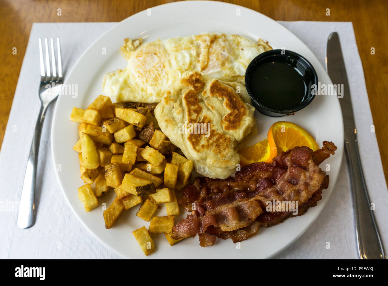 Ein Neufundland Frühstück mit Eiern, Speck, Hash Brown Kartoffeln und toutons mit Melasse. Stockfoto