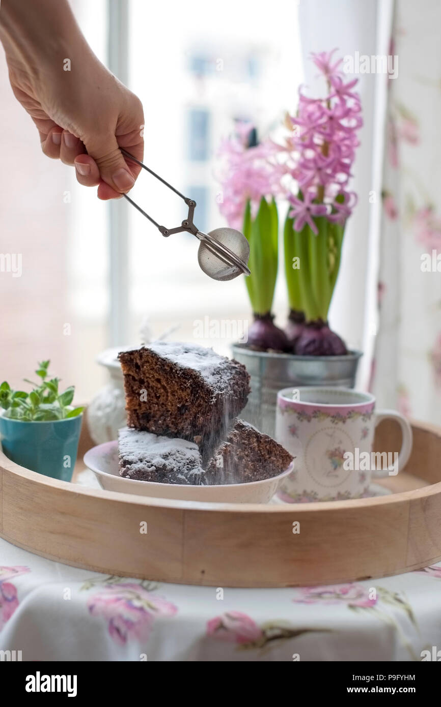 Chocolate Cupcake mit Zucker und Kaffee. Frühstück auf ein Tablett aus Holz und Blumen. Blick aus dem Fenster auf die Stadt Stockfoto