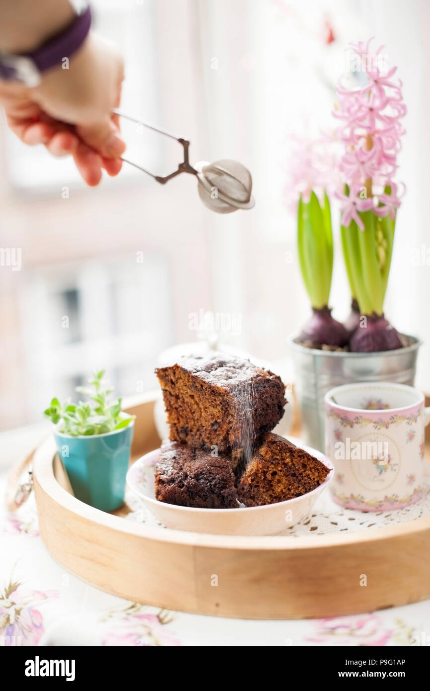 Chocolate Cupcake mit Zucker und Kaffee. Frühstück auf ein Tablett aus Holz und Blumen. Blick aus dem Fenster auf die Stadt. Freier Platz für Text oder eine Postkarte. Stockfoto