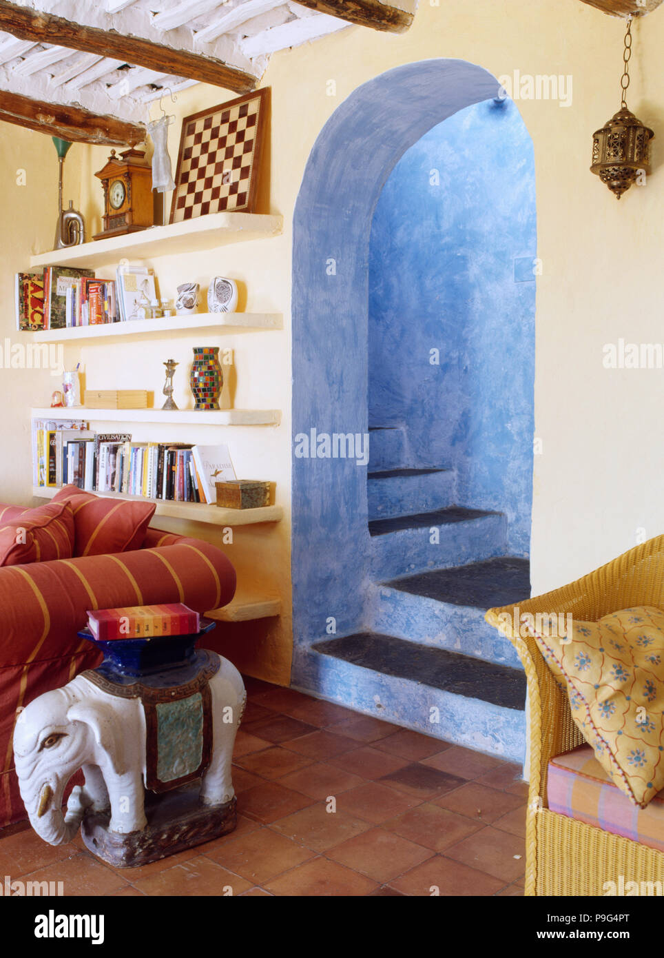 Keramik Elefant Tisch neben Sofa in Spanisch Land leben mit Torbogen mit blauen Wänden auf Treppe Stockfoto