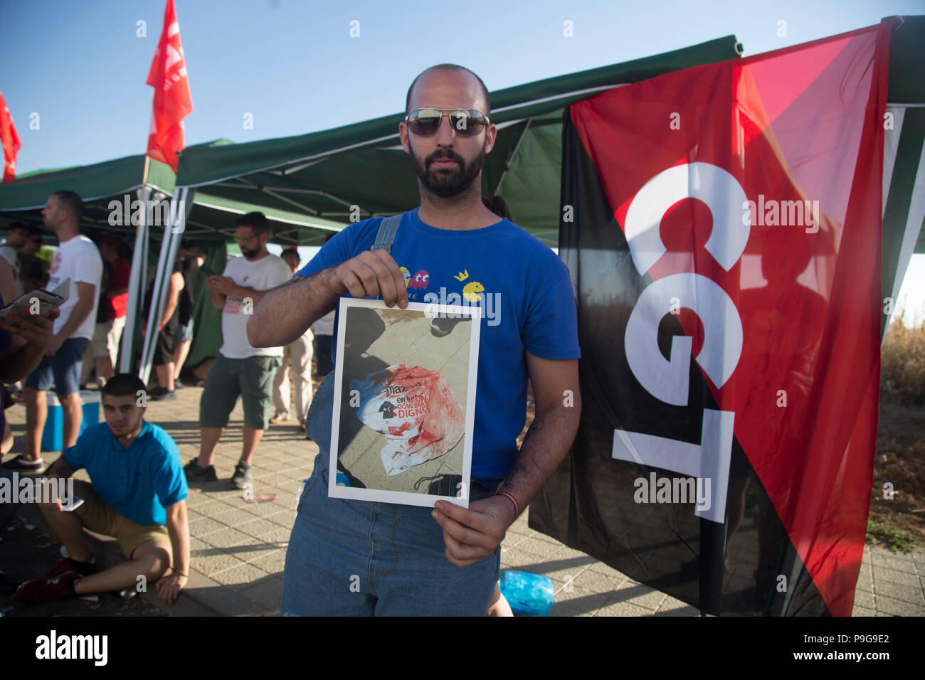 Ein Mann gesehen hält ein Bild mit dem Blut einer der Inhaftierten Polizei Missbrauch zu veröffentlichen. Protest anspruchsvolle für bessere Arbeit und der Freiheit der Arbeiter an der Amazon Lager in San Fernando de Henares. Stockfoto