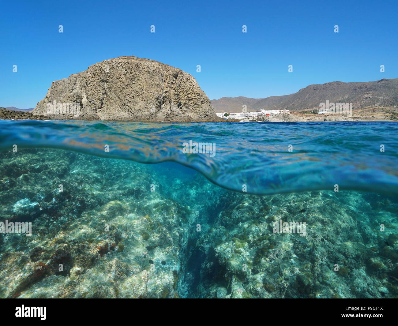 Felsformation an der Küste mit dem Dorf La Isleta del Moro und Felsen unter Wasser, geteilte Ansicht oberhalb und unterhalb der Oberfläche, Mittelmeer, Spanien Stockfoto