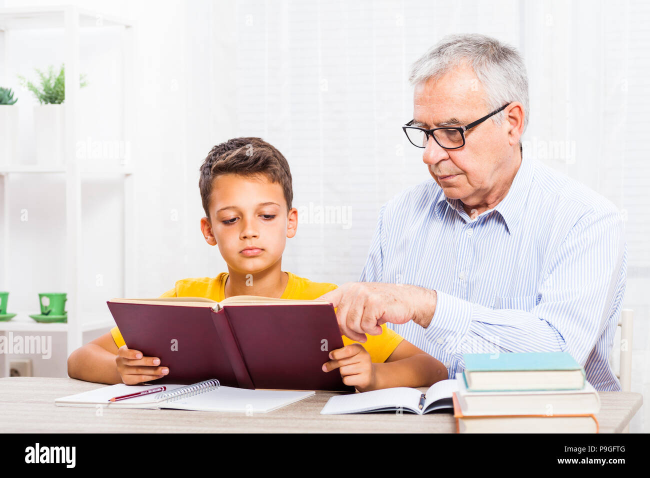 Großvater und Enkel lesen Buch zu Hause. Stockfoto