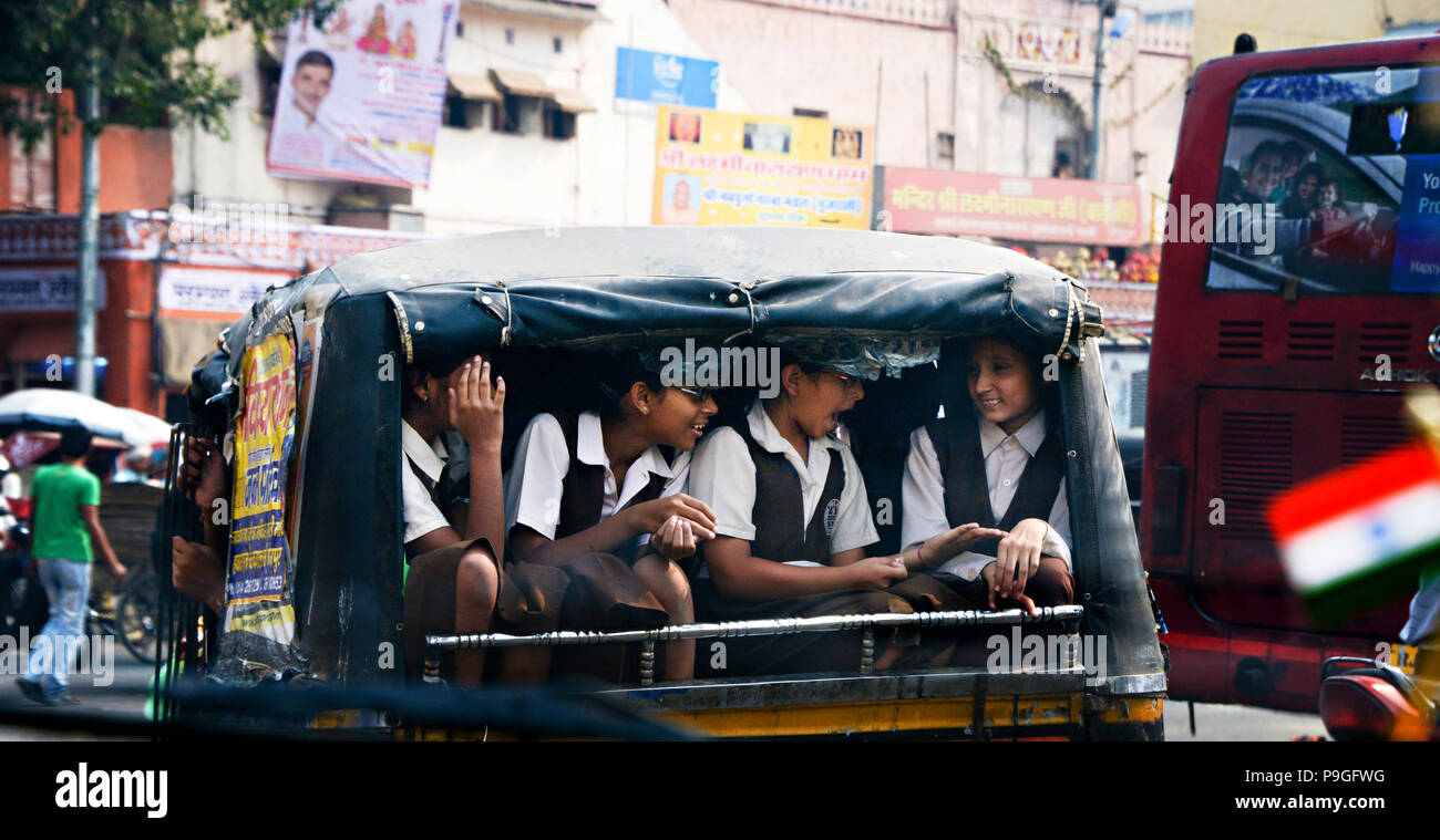 Foto zeigt echte indische Charakter mit Schülerinnen Lachen und Scherzen in einem offenen Lieferwagen oder Lkw in Delhi Indien aus einem fahrenden Fahrzeug fotografiert. Stockfoto