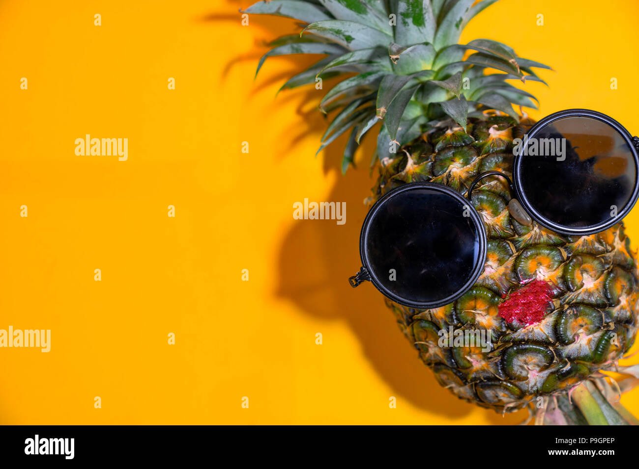 Nahaufnahme reife rote Lippe Ananas mit Sonnenbrille auf gelben Hintergrund, Kopie Raum Stockfoto