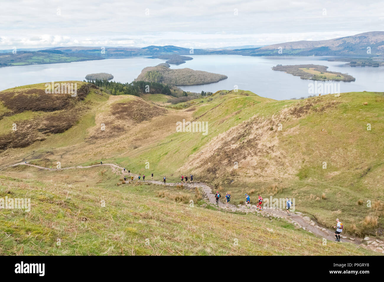 Wettbewerber absteigend Conic Hill mit Blick auf Loch Lomond, Schottland, UK während der Highland Fling Ultra Trail Marathon - April 2018 Stockfoto