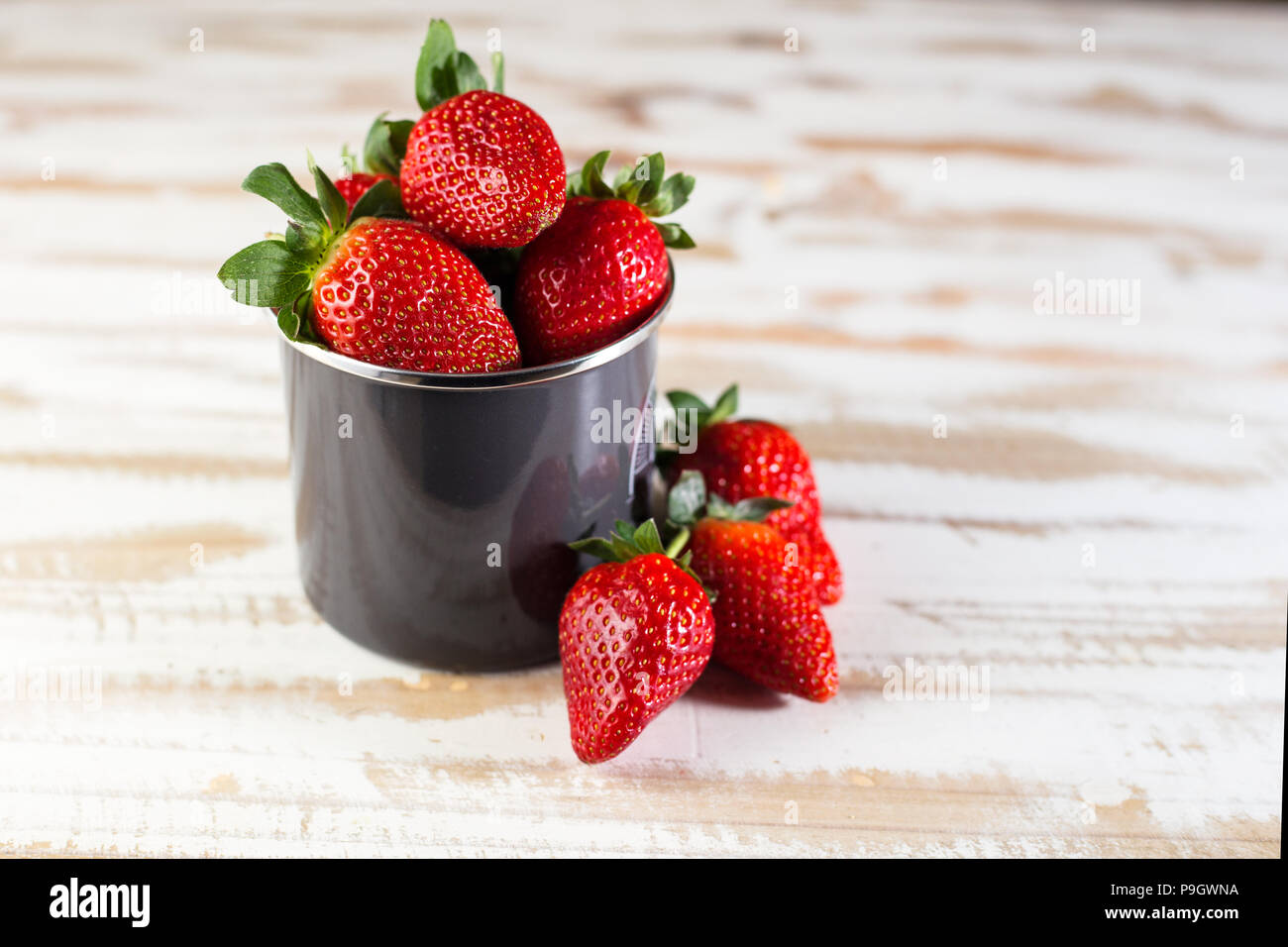 Erdbeeren in grau Emaille Tasse auf weißen Oberfläche Holz, gesundes Essen. Stockfoto