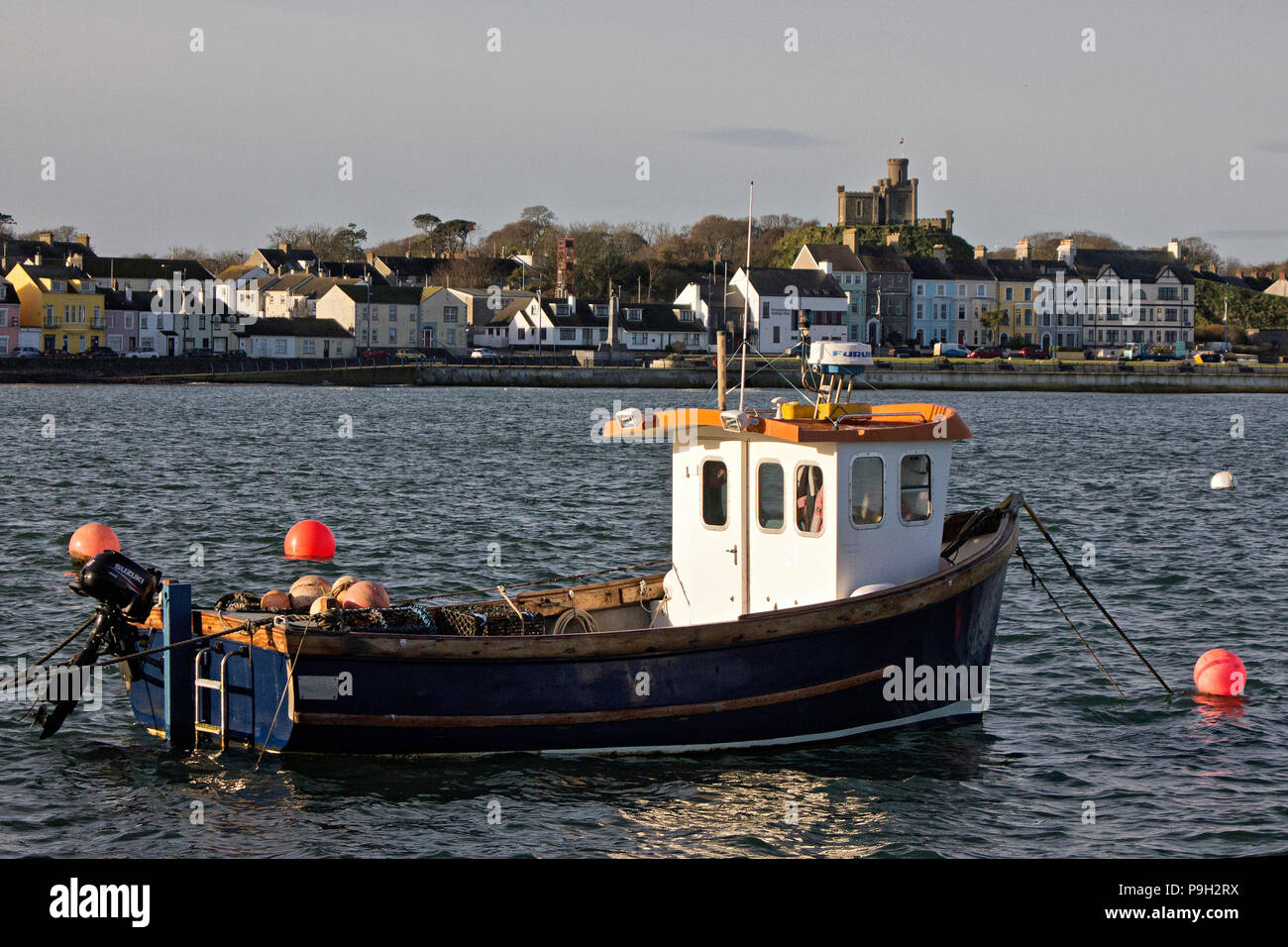 Eine kleine Hummer Fischerboot im Hafen Donaghadee, Nordirland, mit der Stadt und Schiesspulver Storage Magazine hinter sich. Stockfoto