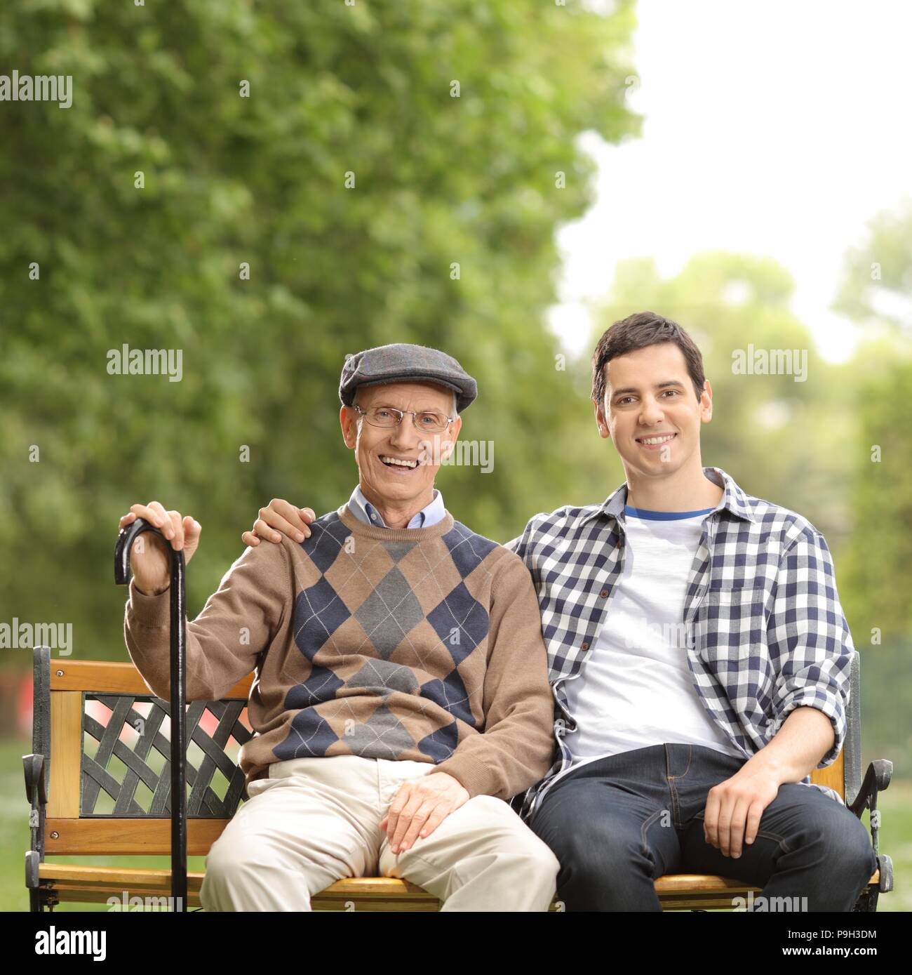 Ältere Menschen und ein junger Kerl sitzen auf einer Bank im Freien Stockfoto