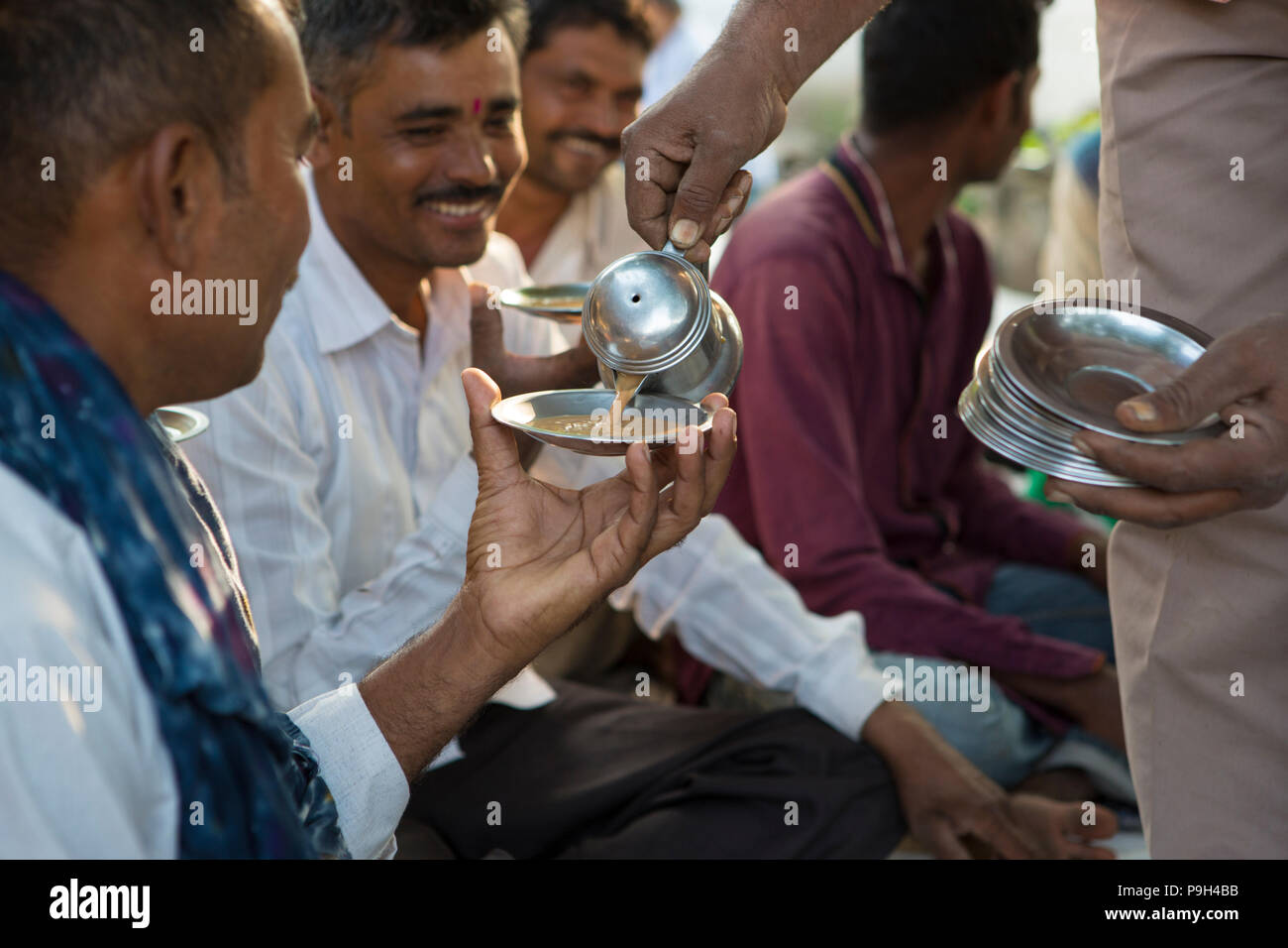 Ein Landwirt drinks Chai, während sich seine lokalen Bauern Interest Group Stockfoto
