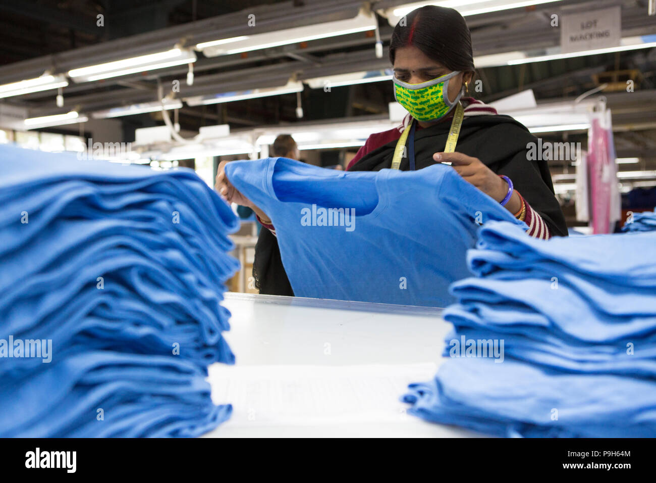 Frauen T-shirts Falten auf einer Produktionslinie in einer Textilfabrik, wo organische Baumwolle verwendet wird Kleidung zu machen, Indore, Indien Stockfoto
