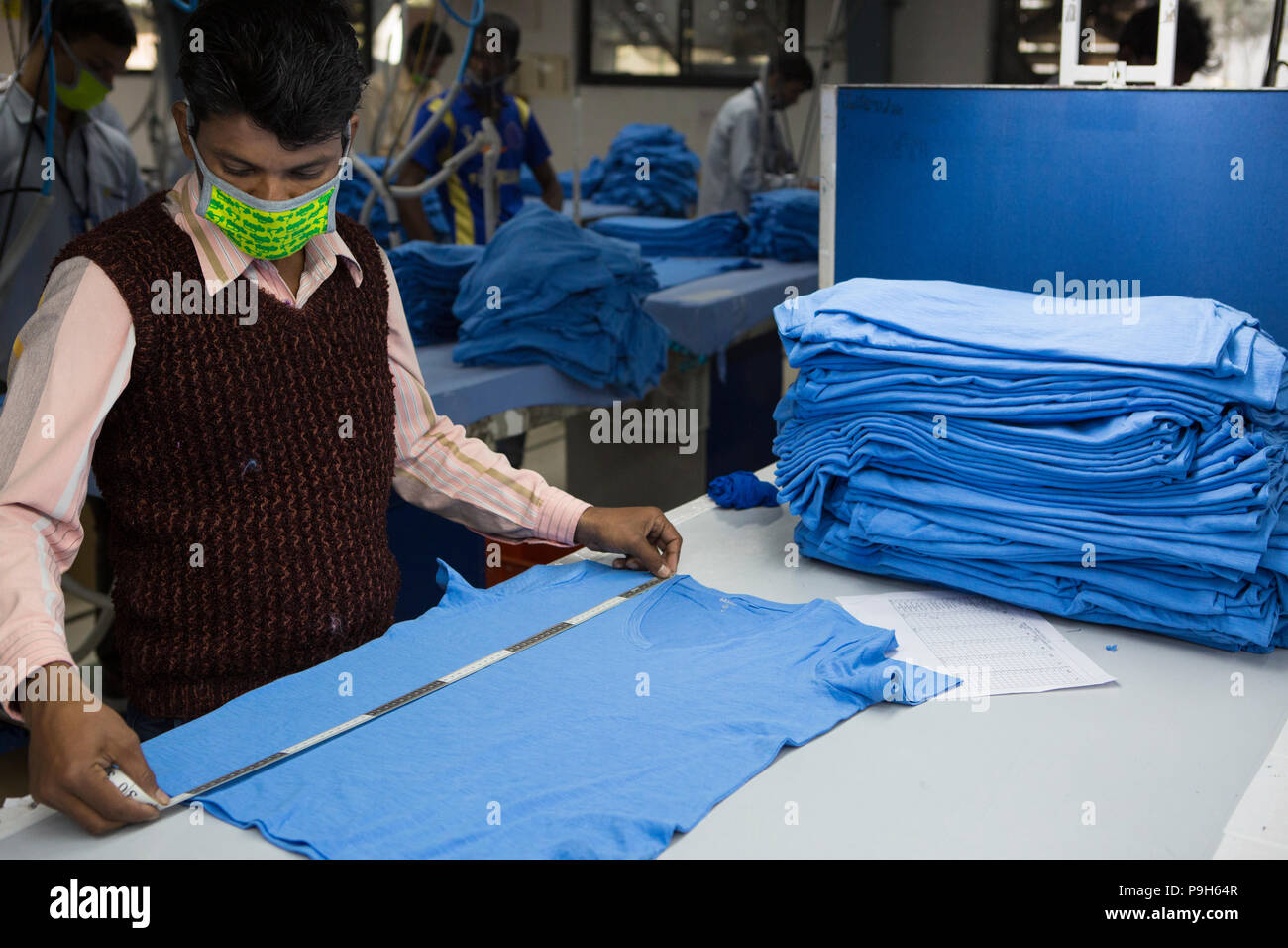 Ein Mann prüft die Messungen von einem T-Shirt in einer Textilfabrik, wo organische Baumwolle verwendet wird Kleidung zu machen, Indore, Indien. Stockfoto
