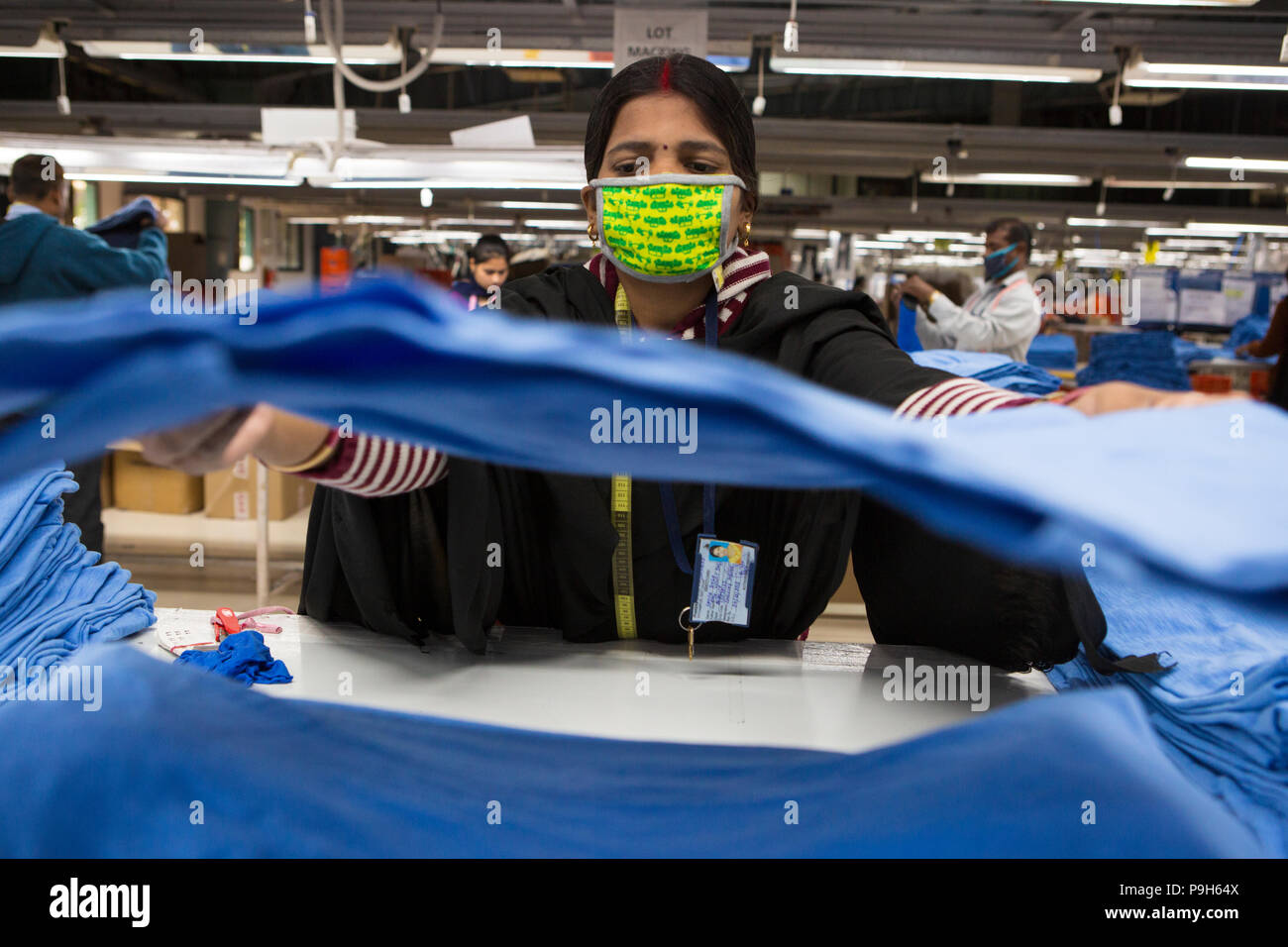 Frauen T-shirts Falten auf einer Produktionslinie in einer Textilfabrik, wo organische Baumwolle verwendet wird Kleidung zu machen, Indore, Indien Stockfoto