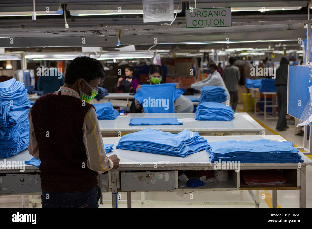 Ein Mann das Falten von T-Shirts auf einer Produktionslinie von einer Textilfabrik, wo organische Baumwolle verwendet wird Kleidung zu machen, Indore, Indien. Stockfoto